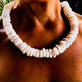 Close-up of a person wearing a necklace made of large, round, puka shells