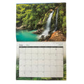 A 2027 wall calendar page showing a tropical waterfall landscape on the top half and a monthly calendar grid on the bottom half, photographed against a plain white background.
