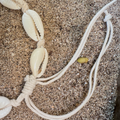 Bracelet with shell-like beads on a sandy surface