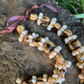 Necklace with white shell rings and marble kukui beads on a dark stone surface