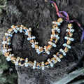 Necklace with white shell rings and marble kukui beads on a dark stone surface