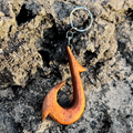 Wooden fish hook keychain on a textured stone surface
