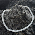White shell choker displayed on a rocky surface

