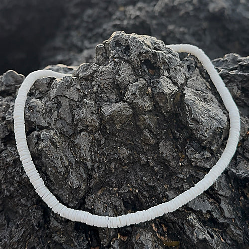 White shell choker displayed on a rocky surface

